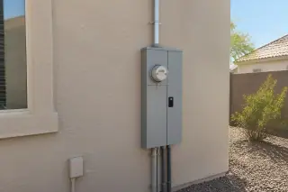 Wide view of a replaced electrical meter box on a stucco wall in Phoenix, AZ.