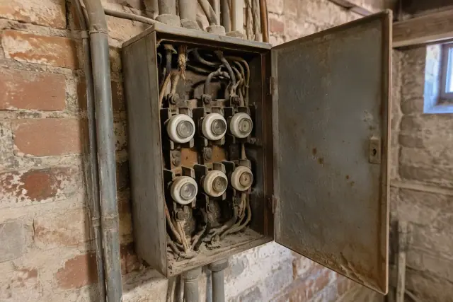 Aged basement brick wall in Phoenix, AZ, featuring an outdated fuse cabinet with vintage cloth wiring.
