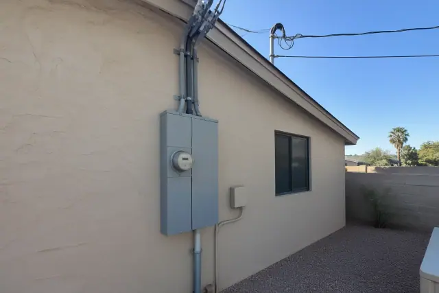 Overhead service entrance upgrade with new cables and meter box on a stucco wall in Phoenix, AZ.