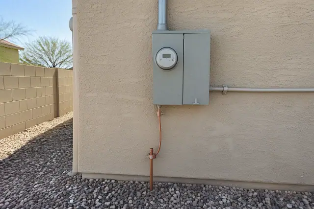 Copper grounding wire attached to a ground rod beneath a utility meter in Phoenix, AZ.