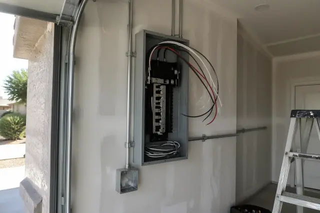 Freshly mounted steel electrical subpanel installation in a residential garage in Surprise, AZ.