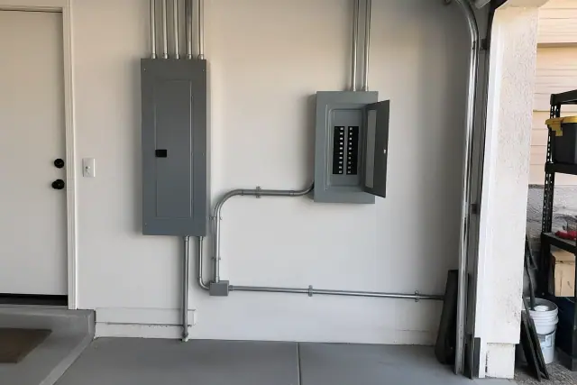 Subpanel installation on a residential garage wall in Avondale, AZ with conduit and a breaker box.
