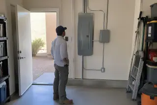 Technician observing a completed subpanel installation on a garage wall in Phoenix, AZ.