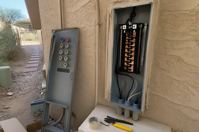 Electrical panel upgrade replacing an old fuse cabinet on a stucco wall in Phoenix, AZ.