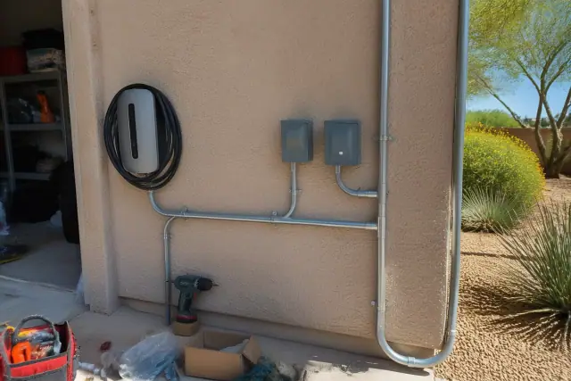 Wall-mounted 240V EV charging unit with conduit piping at a job site in Phoenix, AZ.