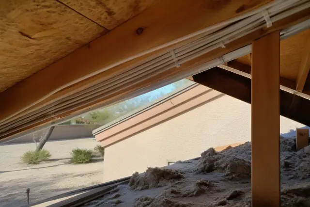 Bundles of new electrical cables stapled to wooden attic rafters during a whole home rewiring project in Phoenix, AZ.