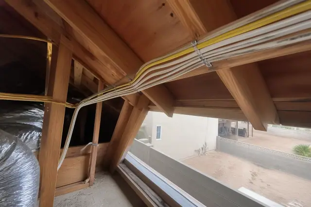 New electrical wiring bundled along wooden rafters during a whole home rewiring project in Phoenix, AZ.