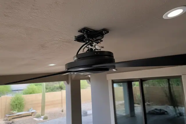 Electrician installing a ceiling fan mounting bracket and wiring in a home in Glendale, AZ.