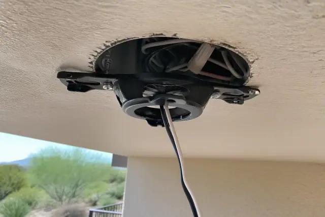 Technician installing a ceiling fan bracket and wiring on a stucco exterior in Paradise Valley, AZ.