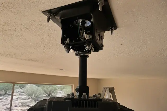 Technician installing a commercial ceiling fan mounting bracket and wiring in a Phoenix, AZ building.
