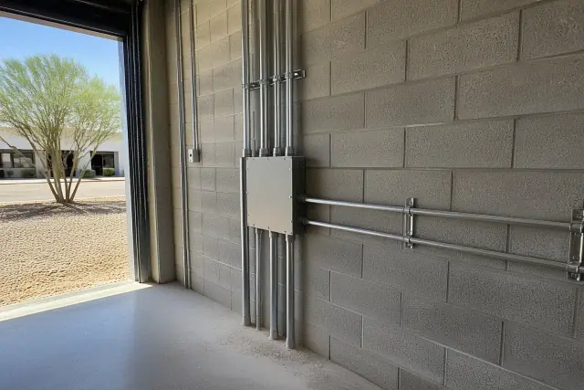 Metal conduit and a junction box installed on a wall at a commercial industrial site in Tempe, AZ.