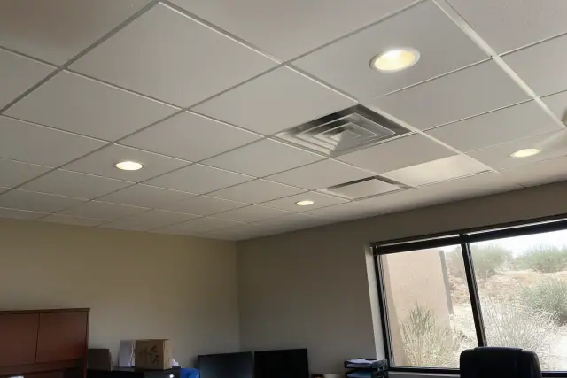 Recessed lighting installed in an office ceiling in Phoenix, AZ, with a view of a stucco wall and desert landscape outside.