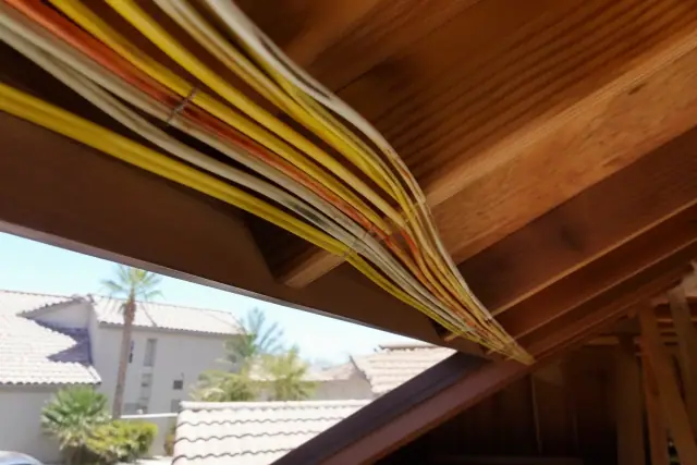 Electrical cables stapled to wooden attic rafters during a whole home rewiring project in Phoenix, AZ.