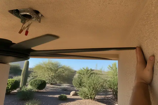 Technician installing a ceiling fan bracket and wiring near a wall in a Phoenix, AZ home.