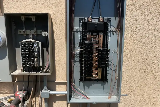 New electrical panel with copper wiring and breakers being installed on a stucco wall in Goodyear, AZ.