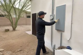 Electrician using a voltage tester on a residential electrical panel at a job site in Phoenix, AZ.