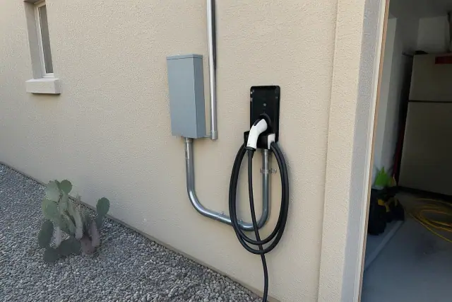 Electrician installing an EV charger on a stucco wall with conduit piping at a home in Chandler, AZ.