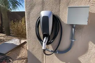 EV charger unit with conduit piping mounted on a stucco wall at a home in Phoenix, AZ.