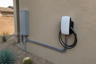 EV charging station mounted on a stucco wall with conduit piping in a Phoenix, AZ home.