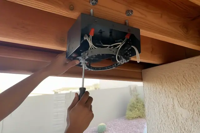 Technician installing a fan-rated electrical box on a ceiling joist at a job site in Phoenix, AZ.