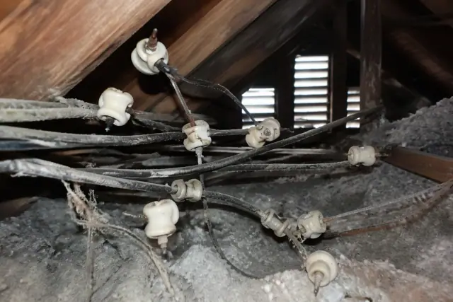 Old knob-and-tube wiring being removed from a dusty attic in Phoenix, AZ.