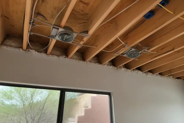 Exposed ceiling joists with wiring and recessed light housings in a Peoria, AZ home under construction.