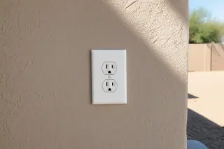 New grounded power receptacle installed on a stucco wall in Phoenix, AZ.