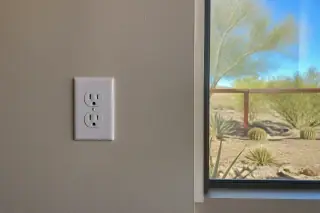 Grounded power outlet with a wall plate on a stucco wall in a Phoenix, AZ home.
