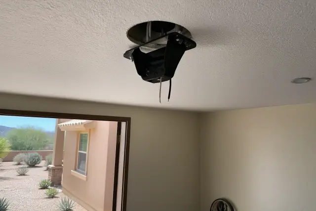 Ceiling fan mounting bracket and wiring installation inside a home in Phoenix, AZ, with desert landscaping visible outside.