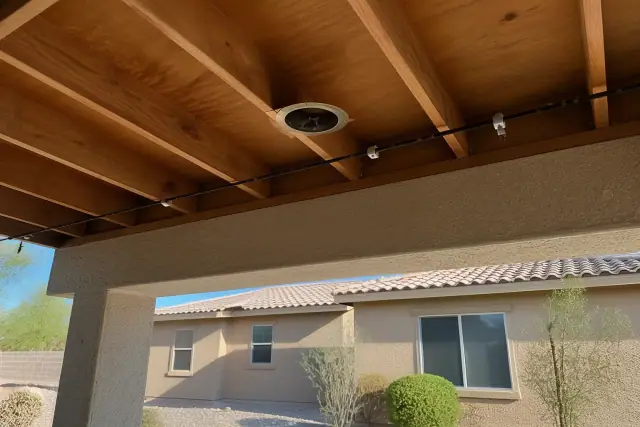 Festive string light clips and cable runs installed on rafters at a Phoenix, AZ jobsite with desert landscaping.
