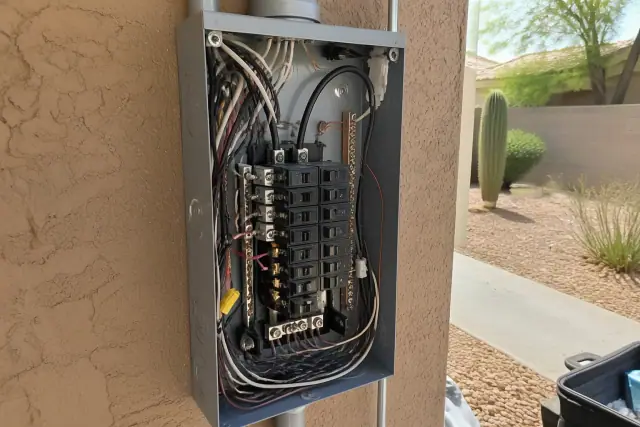Electrician installing a new circuit breaker into a sub-panel in a residential garage in Phoenix, AZ.