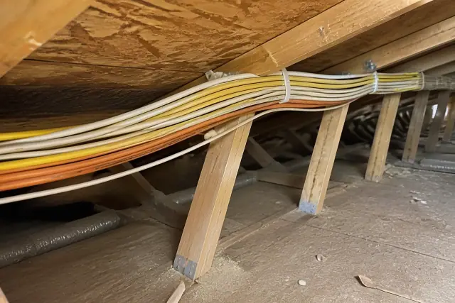 New electrical wiring stapled to wooden attic rafters during a whole home rewiring project in Glendale, AZ.