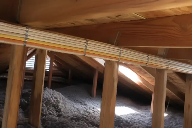 New electrical cables stapled to wooden attic rafters during a whole home rewiring project in Sun City, AZ.