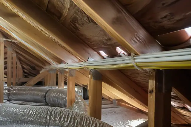 New electrical wiring bundle stapled to wooden attic rafters during a whole home rewiring project in Phoenix, AZ.