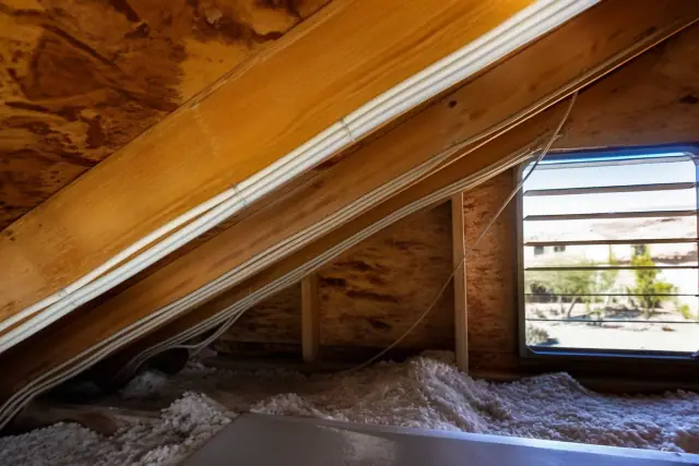 Electrical cables stapled to wooden attic rafters during a whole home rewiring project in Phoenix, AZ.
