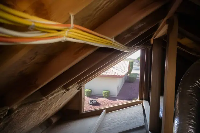 Bundle of electrical cables stapled to wooden attic rafters during a home rewiring project in Peoria, AZ.