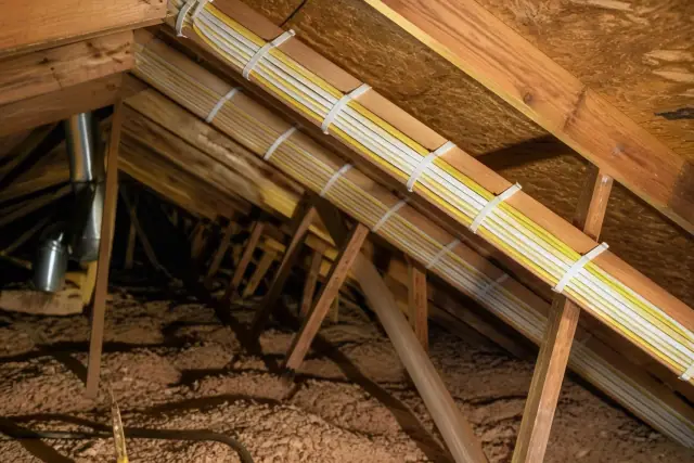 New electrical cables neatly stapled along wooden attic rafters during a whole home rewiring project in Goodyear, AZ.