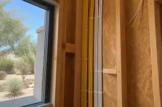 Bundles of new electrical cables neatly stapled to wooden studs in a Phoenix, AZ home.