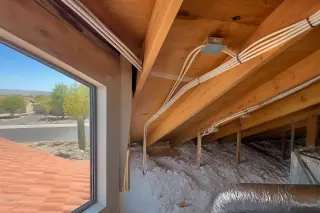 Bundled electrical cables secured along wooden rafters in a Phoenix, AZ home.