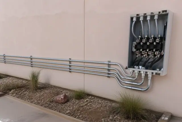 Metal conduit pipes and a junction box installed on a stucco wall at an industrial jobsite in Phoenix, AZ.