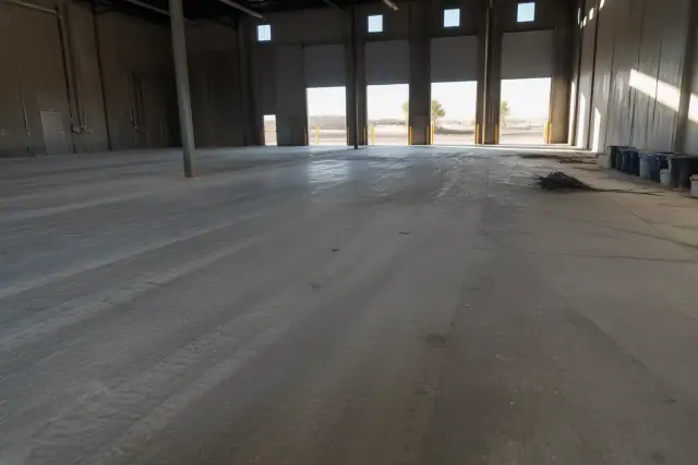 Unfinished dusty concrete floor inside a logistics warehouse in Phoenix, AZ, prepared for an epoxy flooring system.