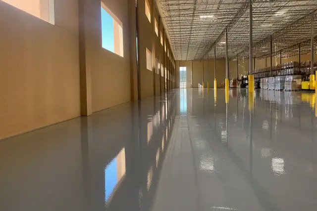High-gloss industrial epoxy flooring in a Phoenix, AZ warehouse with sunlight filtering through clerestory windows.