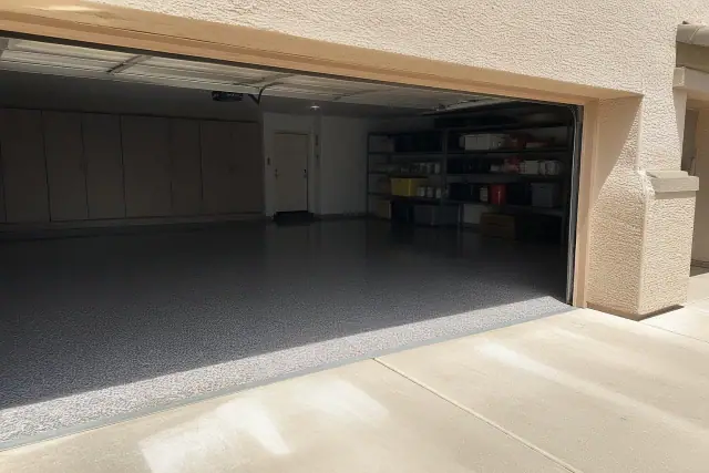 Finished multi-color flake epoxy floor in a residential garage in Chandler, AZ with bright sunlight on the driveway.
