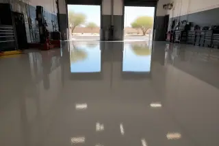 High-gloss epoxy floor in an automotive workshop with desert sunlight streaming through open bay doors in Phoenix, AZ.