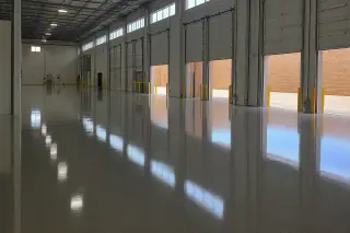 High-gloss epoxy floor in a Phoenix, AZ warehouse reflecting overhead lights and desert sunlight.