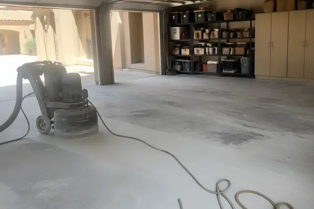 Concrete floor grinder and dust in a residential garage during a flooring project in Phoenix, AZ.