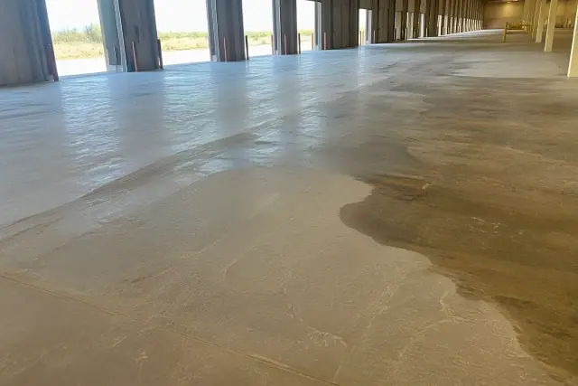Unfinished concrete floor undergoing polishing and staining inside a logistics warehouse in Phoenix, AZ.
