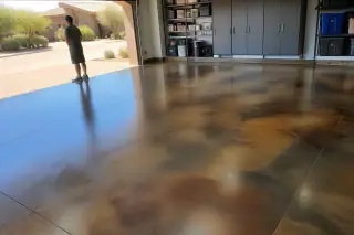 Technician inspecting a stained concrete floor with swirl patterns in a Phoenix, AZ garage with desert views.