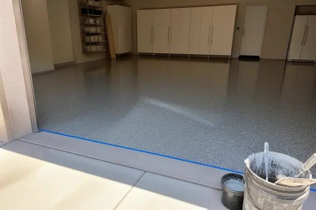 High-gloss flake epoxy floor in a residential garage in Phoenix, AZ, with mixing tools and masking tape.