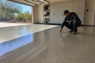 Technician inspecting a glossy speckled epoxy garage floor in a Phoenix, AZ home with desert views outside.